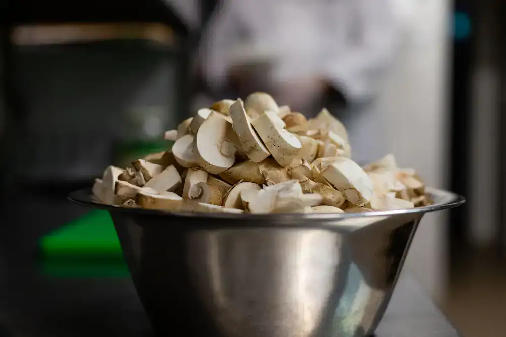Chef inspecting fresh gourmet mushrooms in a professional stainless steel kitchen setting